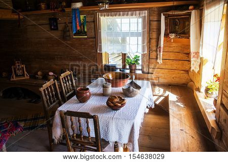 VELIKY NOVGOROD, RUSSIA - AUGUST 10, 2015: Inside a typical wooden house - table with chairs and two sun lighted windows. Museum of wooden architecture called Vitoslavlitsy
