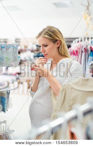 Beautiful pregnant woman in white shirt shopping shoes for her baby