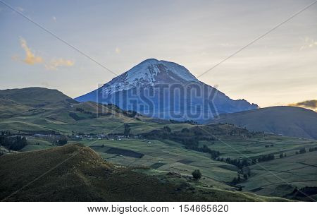 View of the Chimborazo volcano in semi silhouette and surrounding Andes mountains, on a sunny morning. Bolivar Province, Ecuador