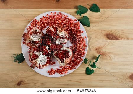 Beautiful ripe pomegranate lying on the wooden light background