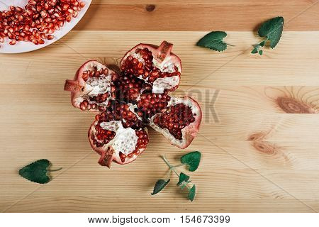 Beautiful ripe pomegranate lying on the wooden light background