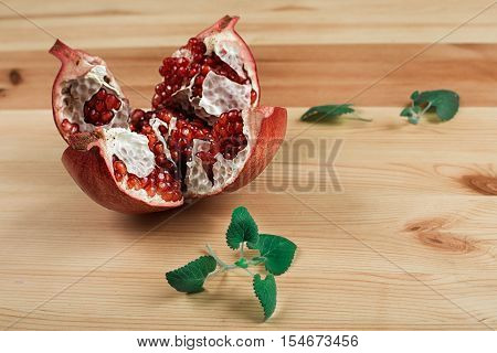 Beautiful ripe pomegranate lying on the wooden light background