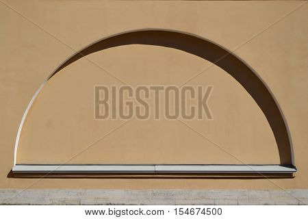 Semicircular false window in a light brown plastered wall