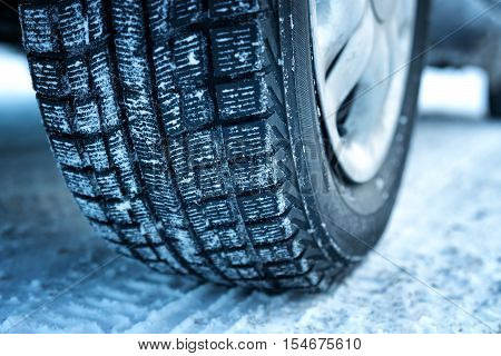 Closeup of car tires in winter on the road covered with snow