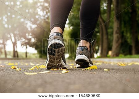 Morning jogging young woman outdoors. Green trees in the background.