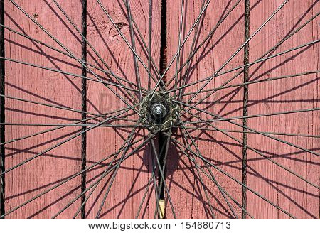 Vintage bicycle wheel on the old red wooden background.