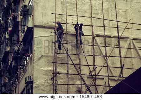 Hong Kong - October 2016: Kowloon street view with man building bamboo scaffolding. Retro look.