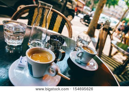 Two espressos on table beside sidewalk at a Parisian cafe