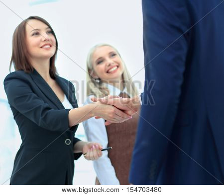 Two business people making agreement, their female colleague sta
