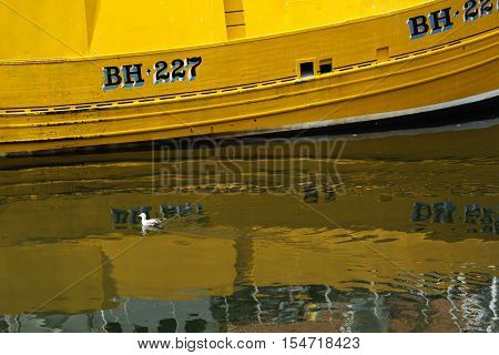 Yellow boat reflection in water. Eyemouth in Scotland UK. 07.08.2015