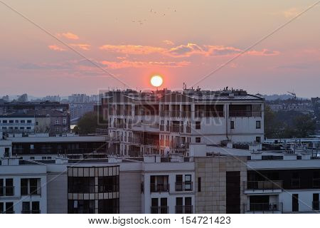 Krakow city architecture with sunset across horizon. Urban background sunny haze dusk time