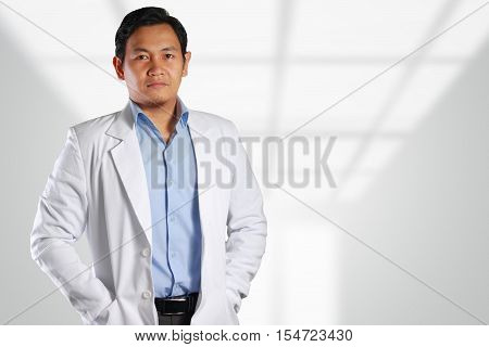Photo image of a handsome attractive confident successful young Asian male doctor smiling to the front with blurred out of focus background