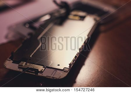 A close-up process of disassemble and dismantle modern mobile phone smartphone with broken shattered display glass and changing details at home