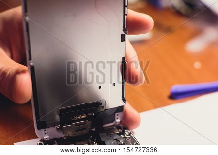 A close-up process of disassemble and dismantle modern mobile phone smartphone with broken shattered display glass and changing details at home