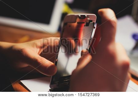 A close-up process of disassemble and dismantle modern mobile phone smartphone with broken shattered display glass and changing details at home