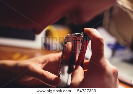 A close-up process of disassemble and dismantle modern mobile phone smartphone with broken shattered display glass and changing details at home