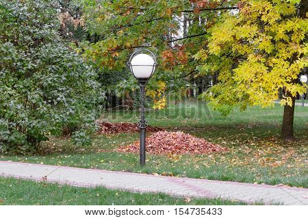 Autumn landscape: the Park in the bushes and trees covered with yellow leaves the leaves lying on the grass. The landscape is decorated with beautiful lantern . Перевести вGoogleBing