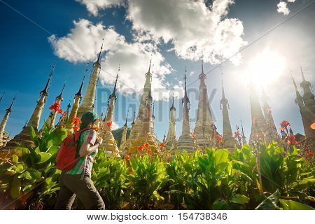 Woman traveling with backpack looking at stupa Buddhist temple Takhaung Mwetaw Pagoda . Myanmar