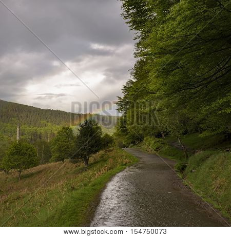 Ancient tower of Glendalough monastery with rainbow in bad weather