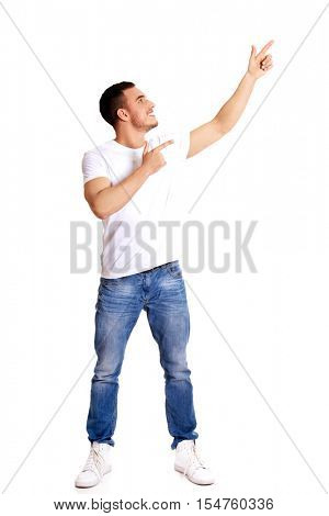 Happy young man pointing at copyspace or something