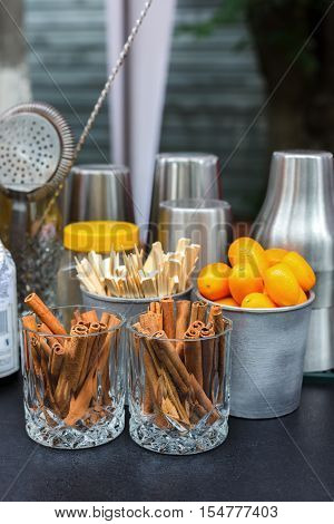 Making mulled wine for sale at country fair. Glintwine accesories, stirring wooden sticks, spices and citrus, cinnamon sticks and kumquat in metal bowls closeup.