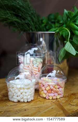 Desserts choice. Marshmallow chewing candies in glass jars on counter bar for sale. Traditional american sweets for sale, closeup, vertical