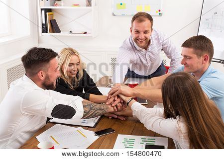 Team put hands together, show connection and alliance. Teambuilding in the office, young businessmen and women in casual unite hands for teamwork and cooperation at new project.