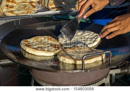 The vendor is  fried roti mataba in the pan