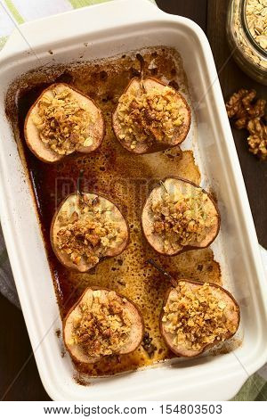 Sweet baked pear halves topped with a crisp crust of oatmeal sugar and walnut sprinkled with cinnamon photographed overhead with natural light (Selective Focus Focus on the top of the crusts)