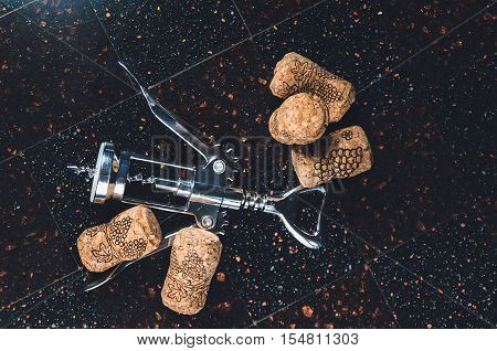 corkscrew with corks lies on a stony table-top