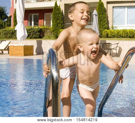 Two litle boys of ffour and five years near swimming pool