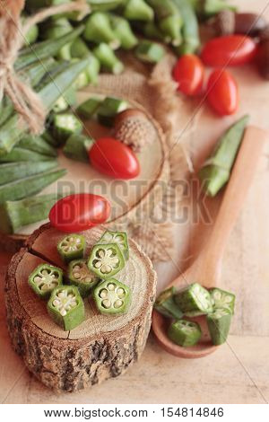 Fresh okra pods and sliced on wood background