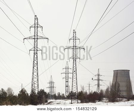 Electricity pylons power lines and cooling tower of the power plant near Kyiv (Ukraine) in winter.
