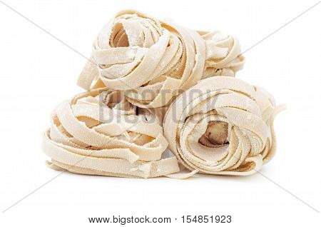 Pile of uncooked rolled traditional italian pasta. Portion of raw fettuccine or tagliatelle or pappardelle. Dry pasta from whole wheat flour. Ingredients for tasty dish.
