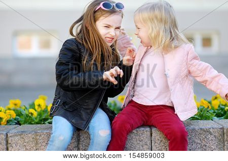 Two little sisters fighting outdoors on summer day