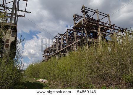 Abandoned factory of synthetic rubber overgrown by trees, ruins of buildings