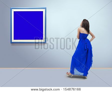 Woman standing inside a gallery in front of blank picture frames.Filmgrain is added for better impression