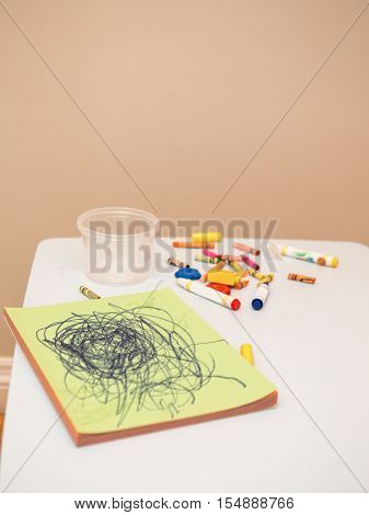 Colored pencils and markers with album drawing on white children table near simple light background with copyspace for text