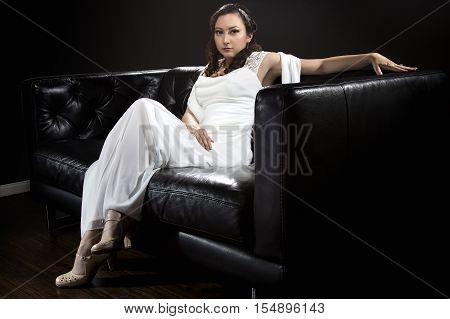 Bridal modeling modern fashion trend of simple but elegant thin wedding dress in retro or art deco style. Bride on couch with shoulder scarf and bridal gown.