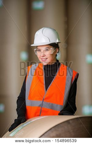 Paper mill factory female worker with giant paper rolls on the background