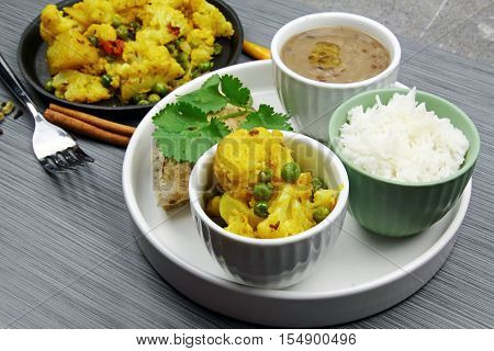 A platter with cauliflower dry curry urad daal or brown lentils rice and chapati selective focus.