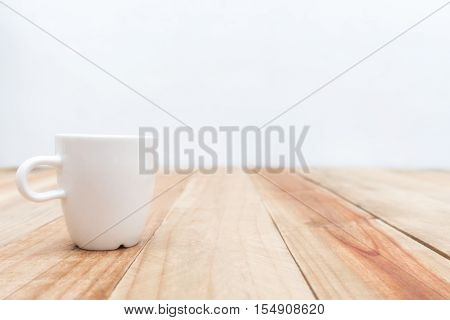 White cup on wooden table and cement wall backgroundSoft focus