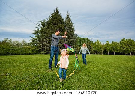 Happy Family.mother, Father, Children  Running Over A Green Meadow. Fly A Colorful Kite.
