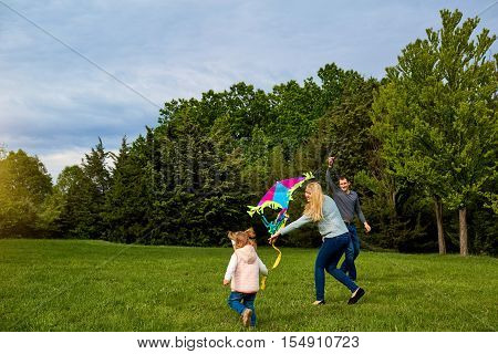 Mom, Dad And Child Flying A Kite. Happy Family Playing, Smiling And Laughing.