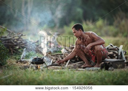 The old man was boiling a kettle of water for tea in the traditional way of life in the countryside.