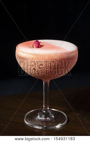 Cocktail made from plum juice decorate with rose in black background