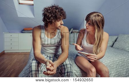 Young woman holding pregnancy test and having a discussion with a unemotional man. Couple intimate problems concept.