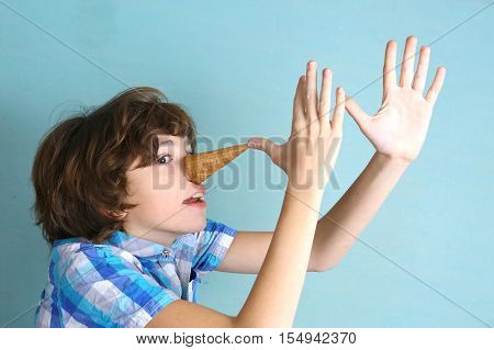 preteen handsome boy grimacing with icecream cone performing pinocchio close up funny photo
