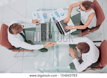 Happy smiling business people shaking hands after a deal in offi