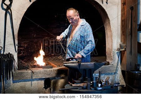Ruzomberok Slovakia - June 30 2012: Blacksmith working metal on the anvil in the forge. Metal products handmade in the workshop